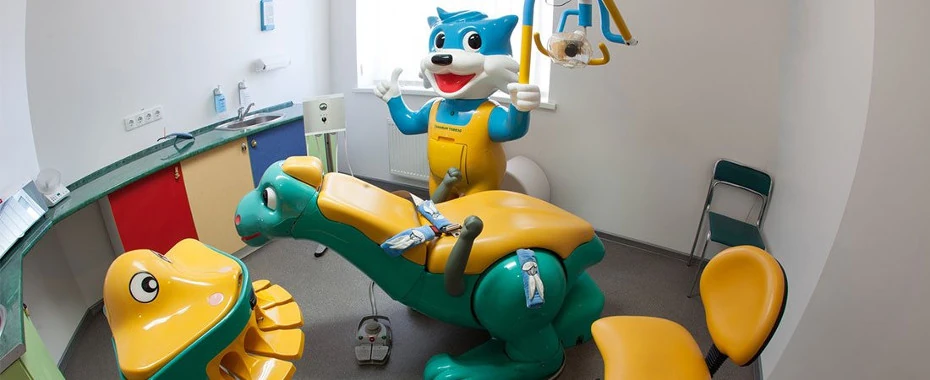 фото дитячого стоматологічного кабінету в клініці Багіта в Черкасах, крісло у вигляді дракончика, поруч усміхнений кіт-світильник, підставки і шафки різнокольорові